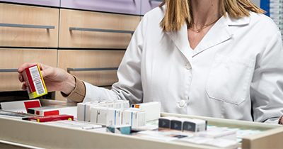 pharmacist organizing medication in a pharmacy with multiple boxes arranged neatly displaying labels and colors related to health and wellness 3 different types of medication