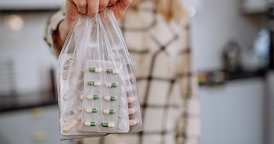 person holding a plastic bag with various medication packets including capsules and tablets showcasing 6 types of pills