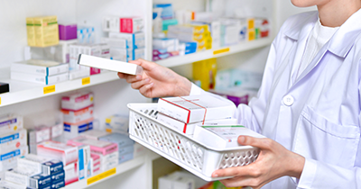 person in a lab coat organizing medication boxes on a pharmacy shelf 14 health products visible 14 pharmaceutical items