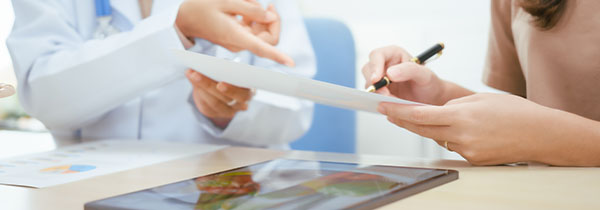 two medical professionals discussing documents while seated at a table with a tablet displaying visuals and charts related to health and wellness 16 benefits 16 guidelines 16 insights