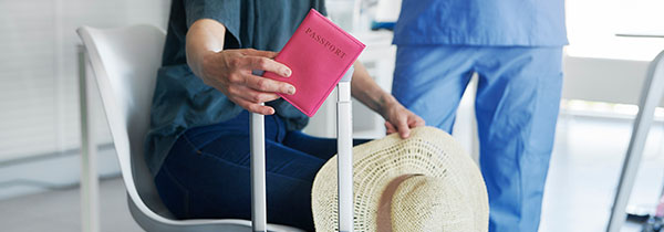 person holding a pink passport next to a suitcase and a straw hat in a waiting area related to travel for a trip or vacation planning 9 destinations